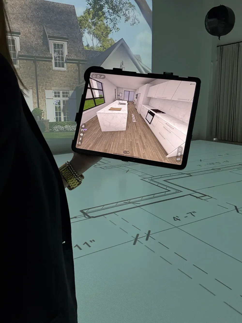 Tablet displaying an interactive 3D kitchen rendering with a full-scale home exterior projected behind it.