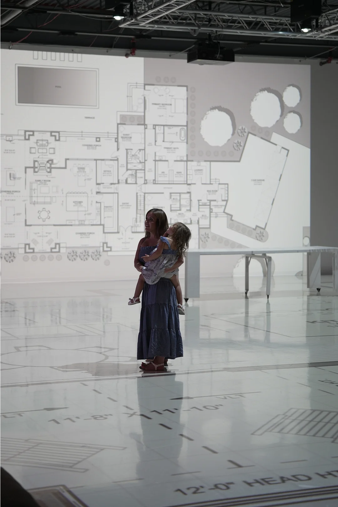 Homeowner and child standing inside a full-scale projection of their new home floor plan