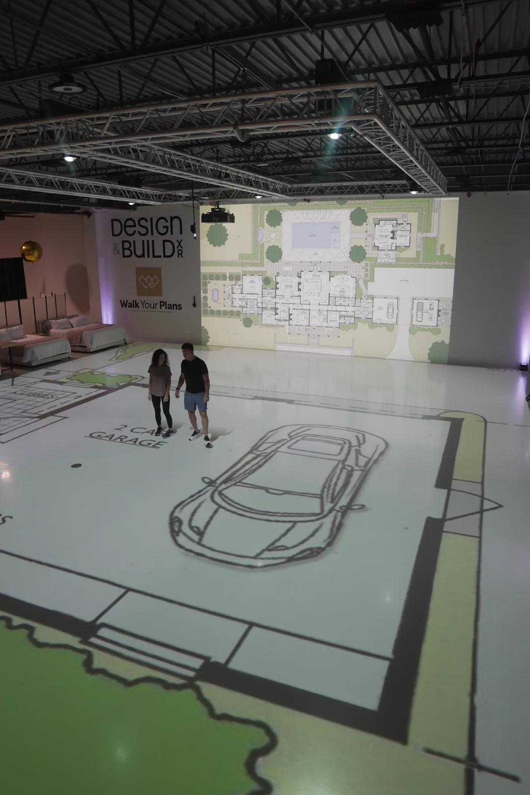 Visitors walking through a projected floor plan showing the two-car garage layout at full scale