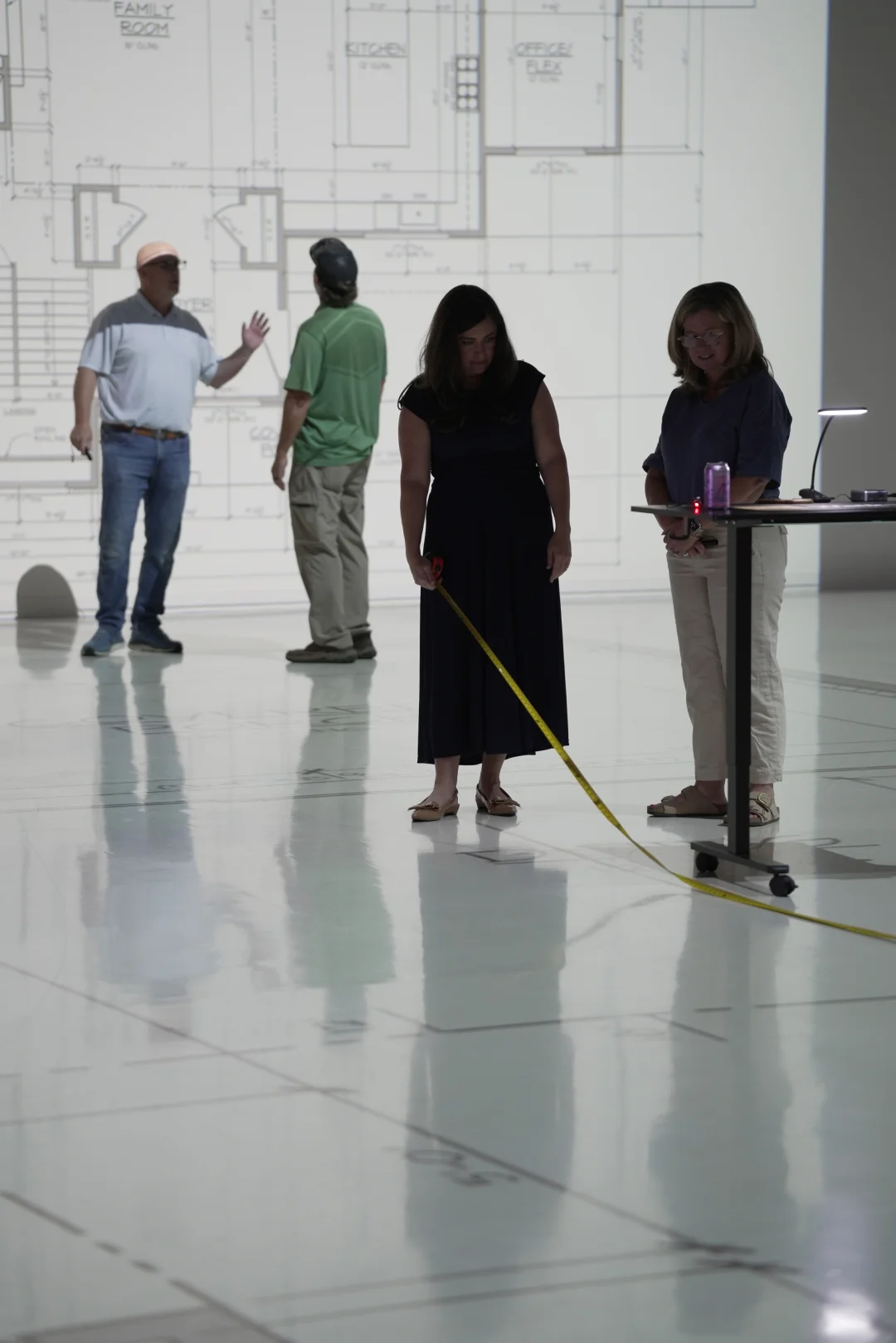 Clients measuring room dimensions with a tape measure during a full-scale walkthrough