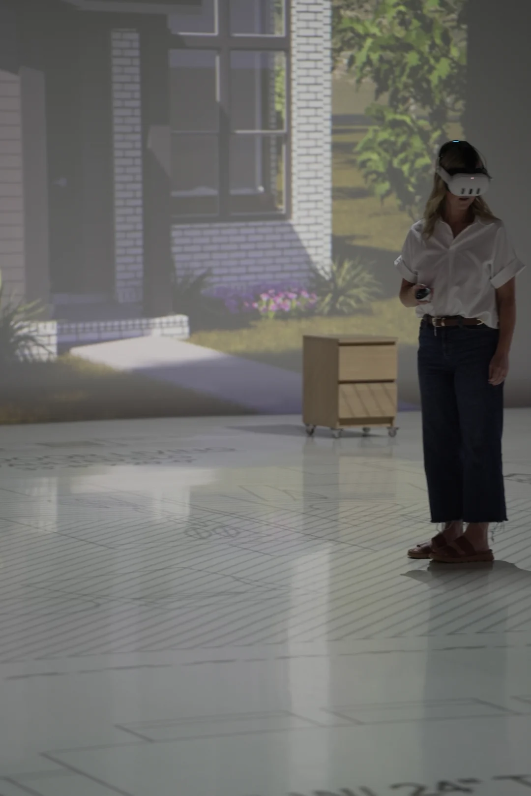 Woman using a VR headset to preview a home exterior design while standing on the projected floor plan.