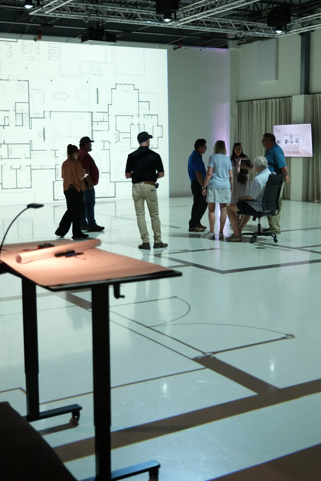 Group gathered on a projected floor plan during a full-scale walkthrough session