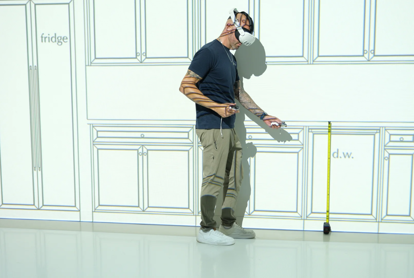Man in a VR headset checking kitchen cabinet heights against a full-scale elevation
