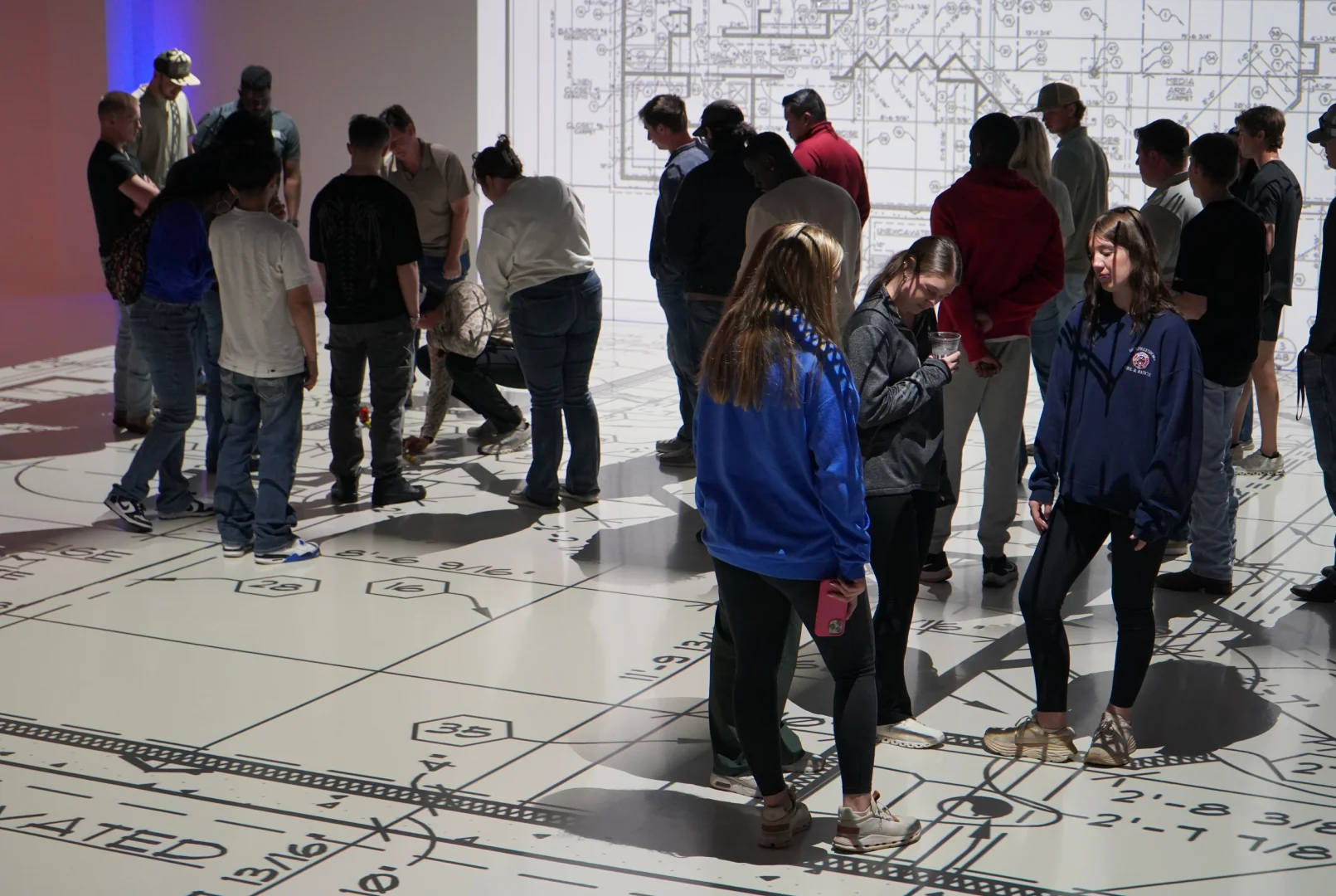 Group of students walking a full-scale floor plan projection together