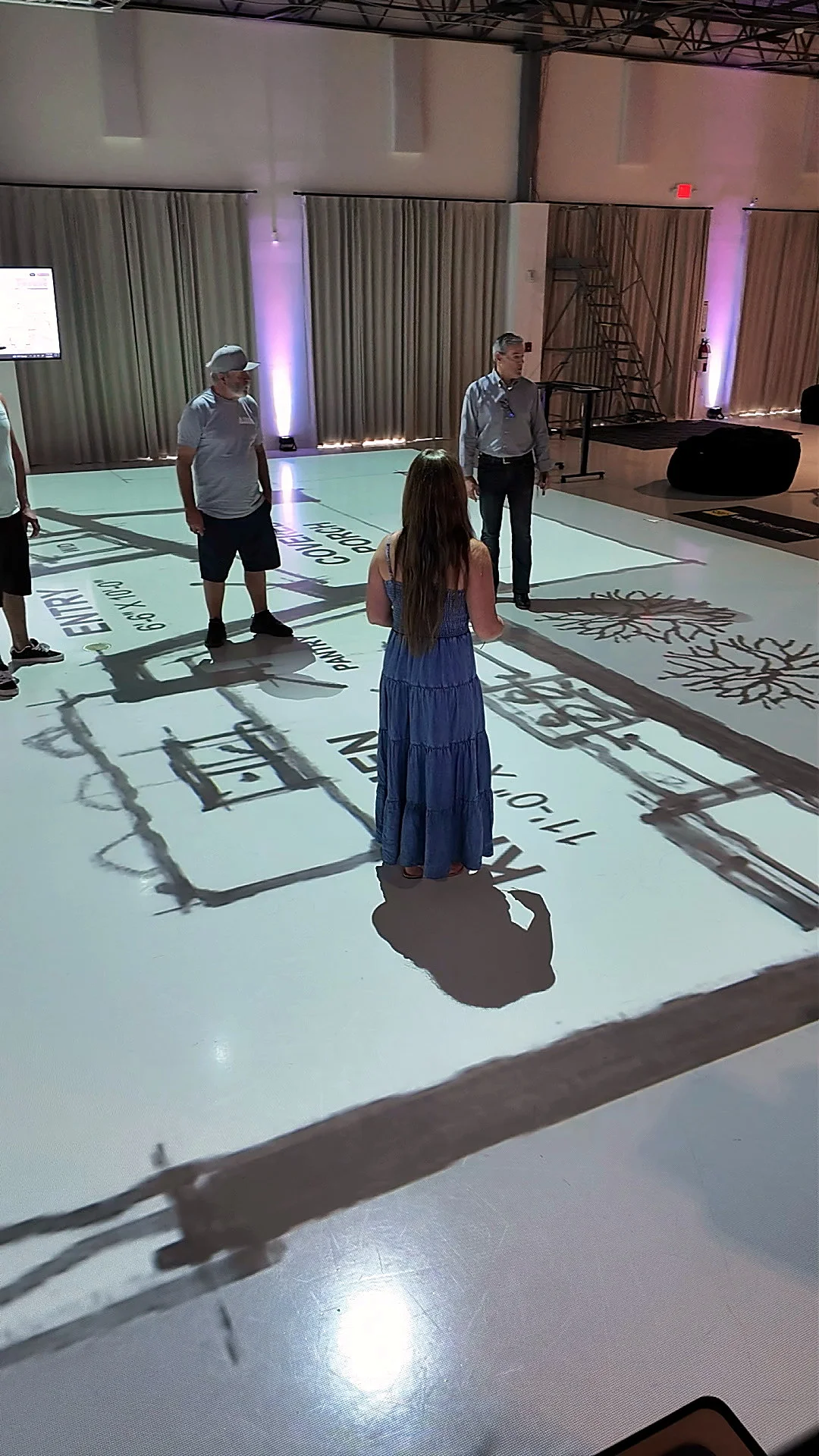 Woman walking through a full-scale floor plan projected on the studio floor