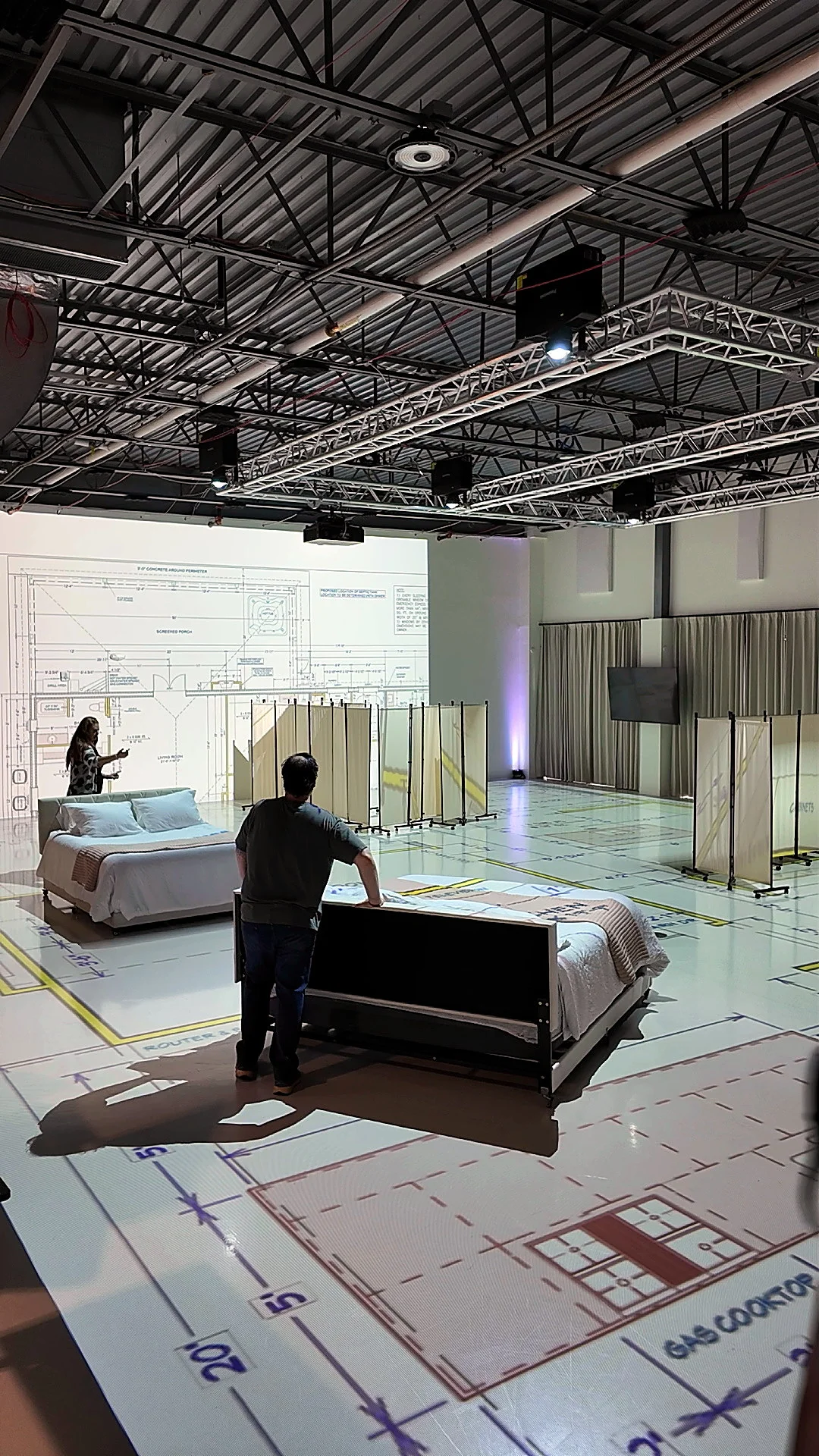 Bedroom furniture staged on a full-scale projected floor plan in the Walk Your Plans Nashville studio to help with pre-sell. 