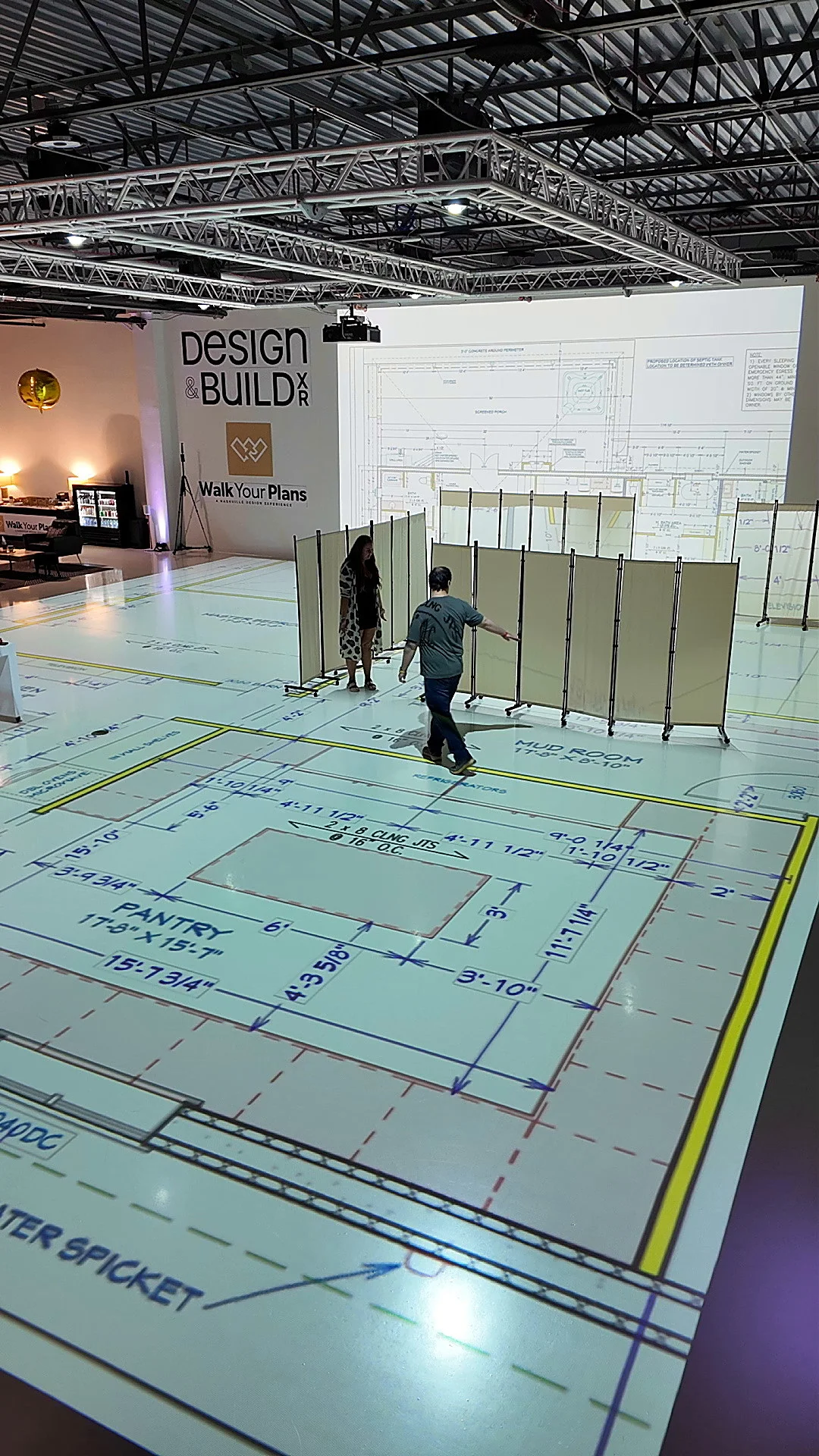 Visitors walking through a full-scale projected floor plan at a Walk Your Plans Design and Build XR event