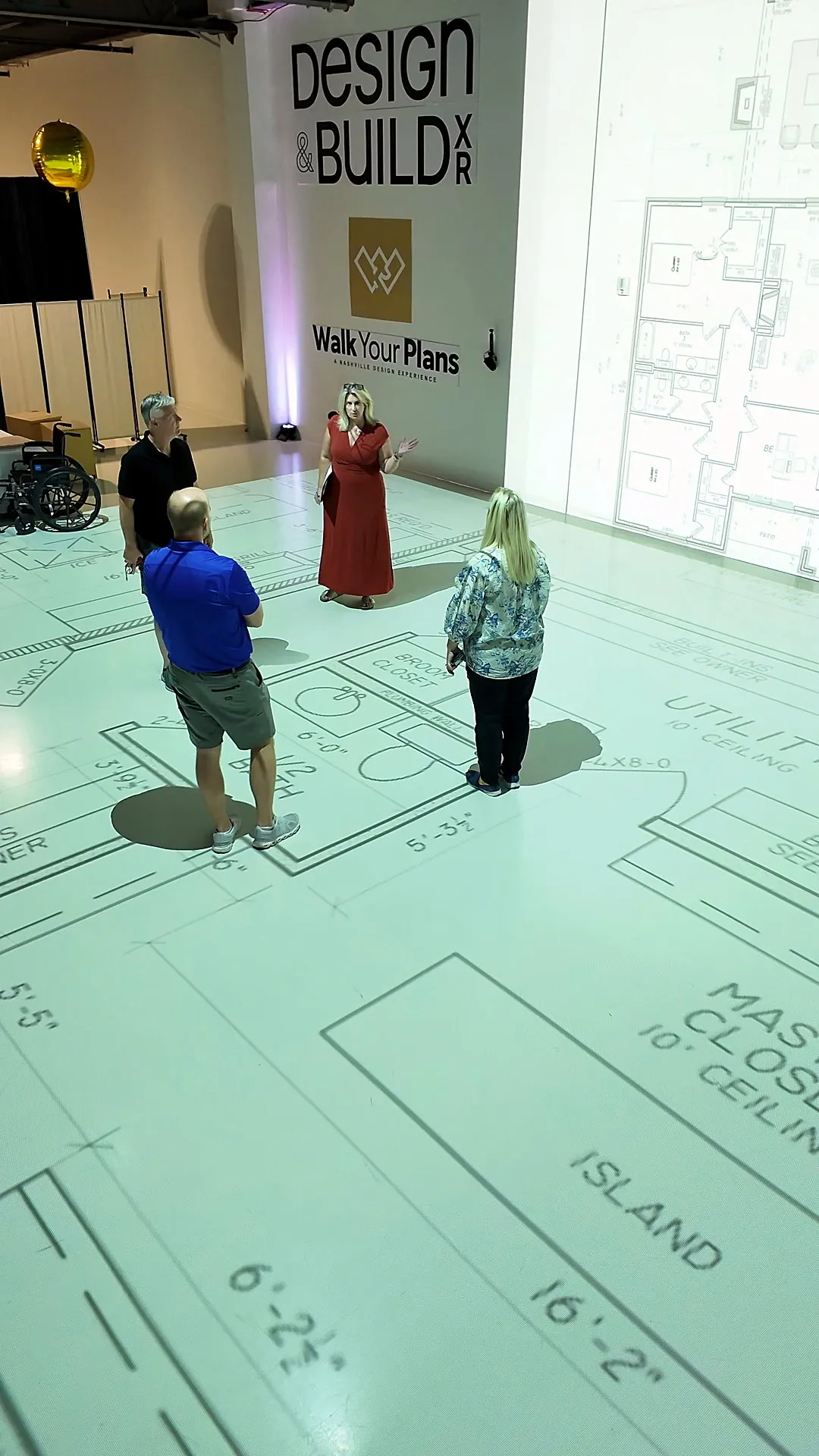 Family walking a full-scale floor plan with the kitchen island and closet projected at 1:1 scale