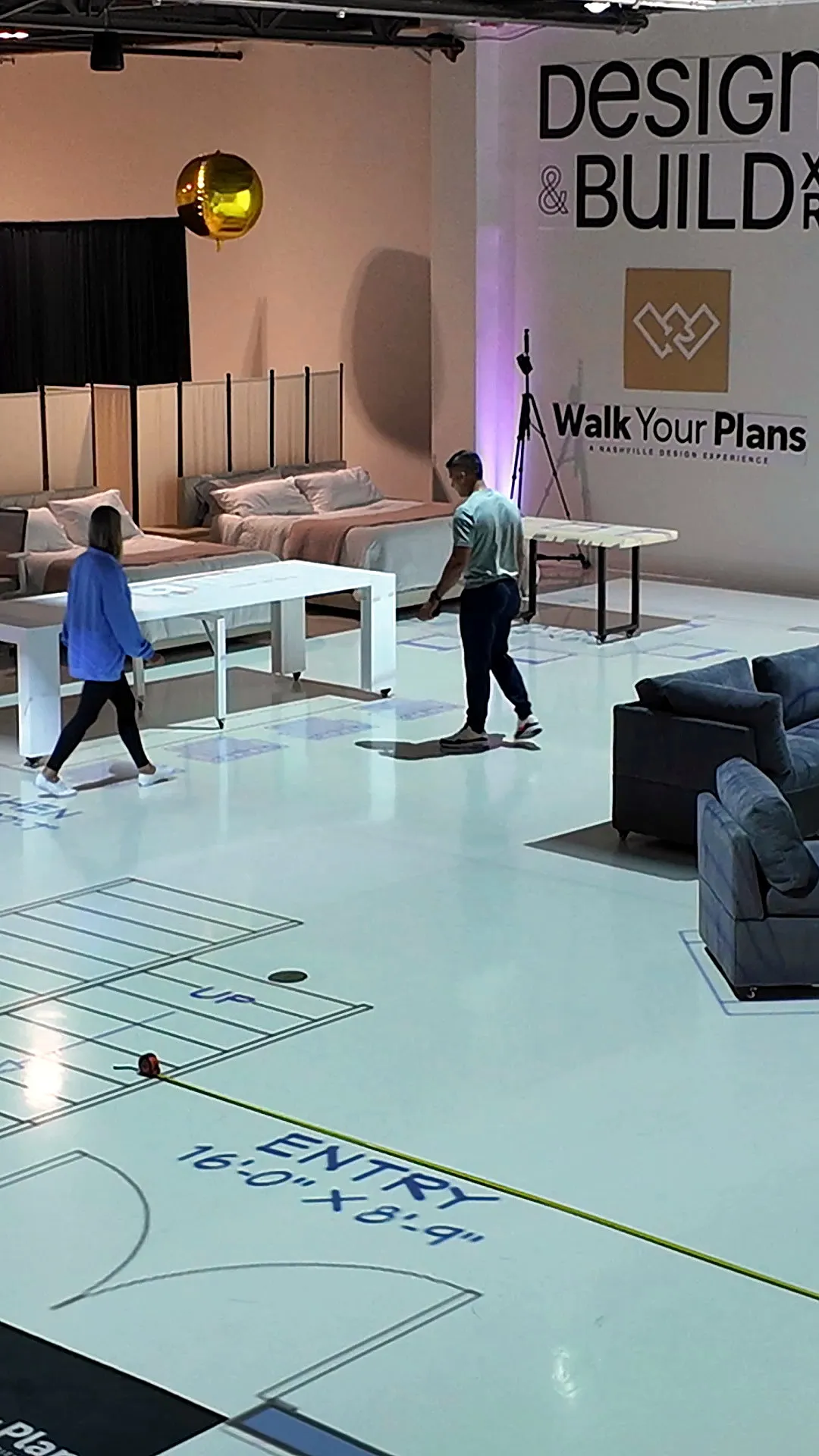 Clients walking the entry of a life size floor plan with real furniture in place